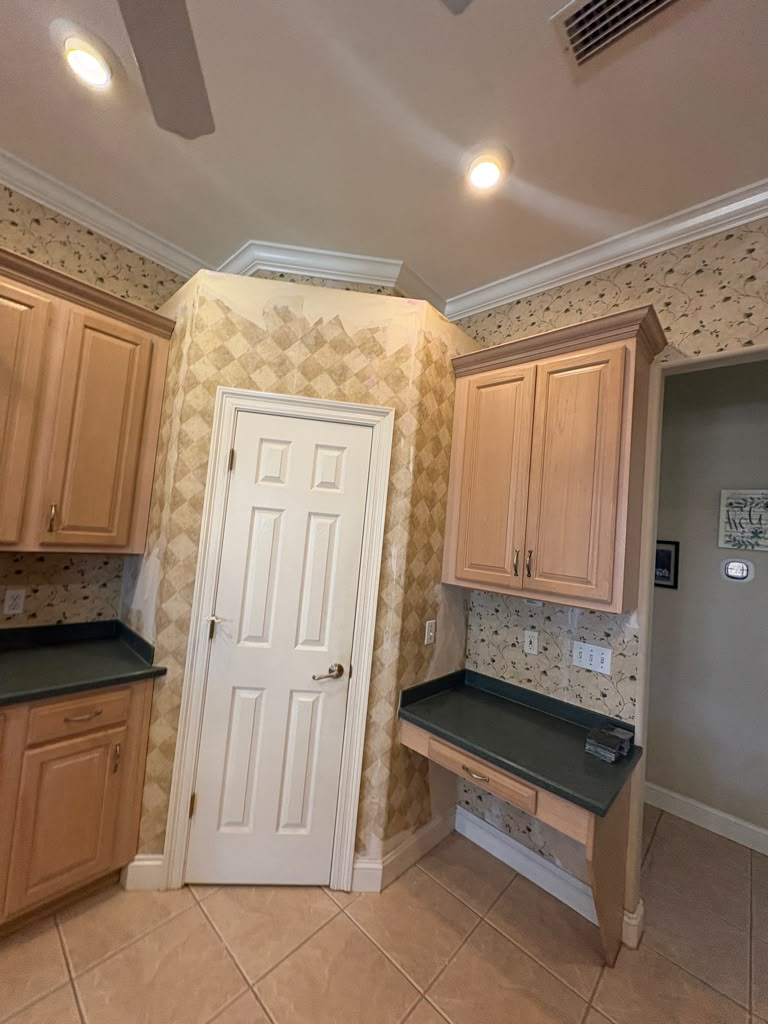 Kitchen before — walls covered in dated harlequin-pattern wallpaper